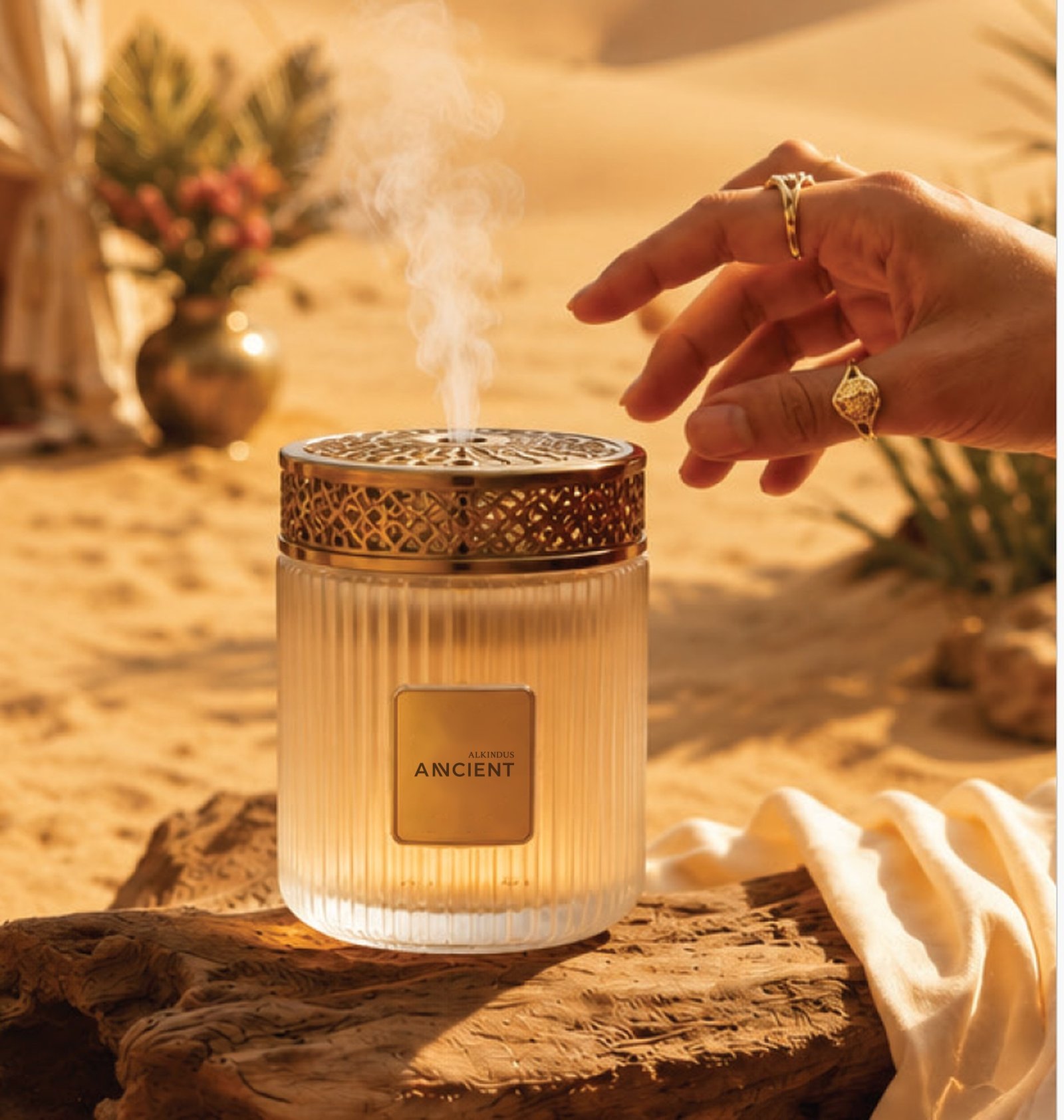 Ornate gold-capped fragrance diffuser jar on driftwood in the desert beside a luxury tent